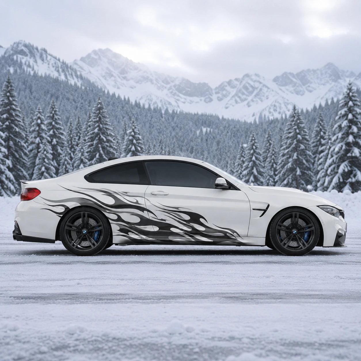 White BMW M4 with black tribal flame side decal in snowy alpine landscape – full side profile