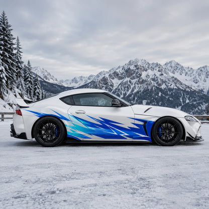 White Toyota Supra GR with blue lightning spike side decal – full side profile in snowy alpine mountain landscape