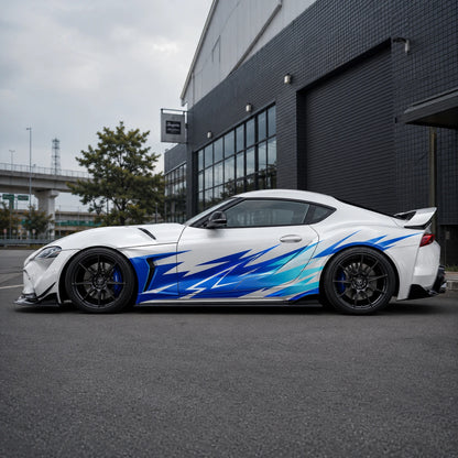 White Toyota Supra GR with blue lightning spike side decal – full side profile in urban JDM garage setting