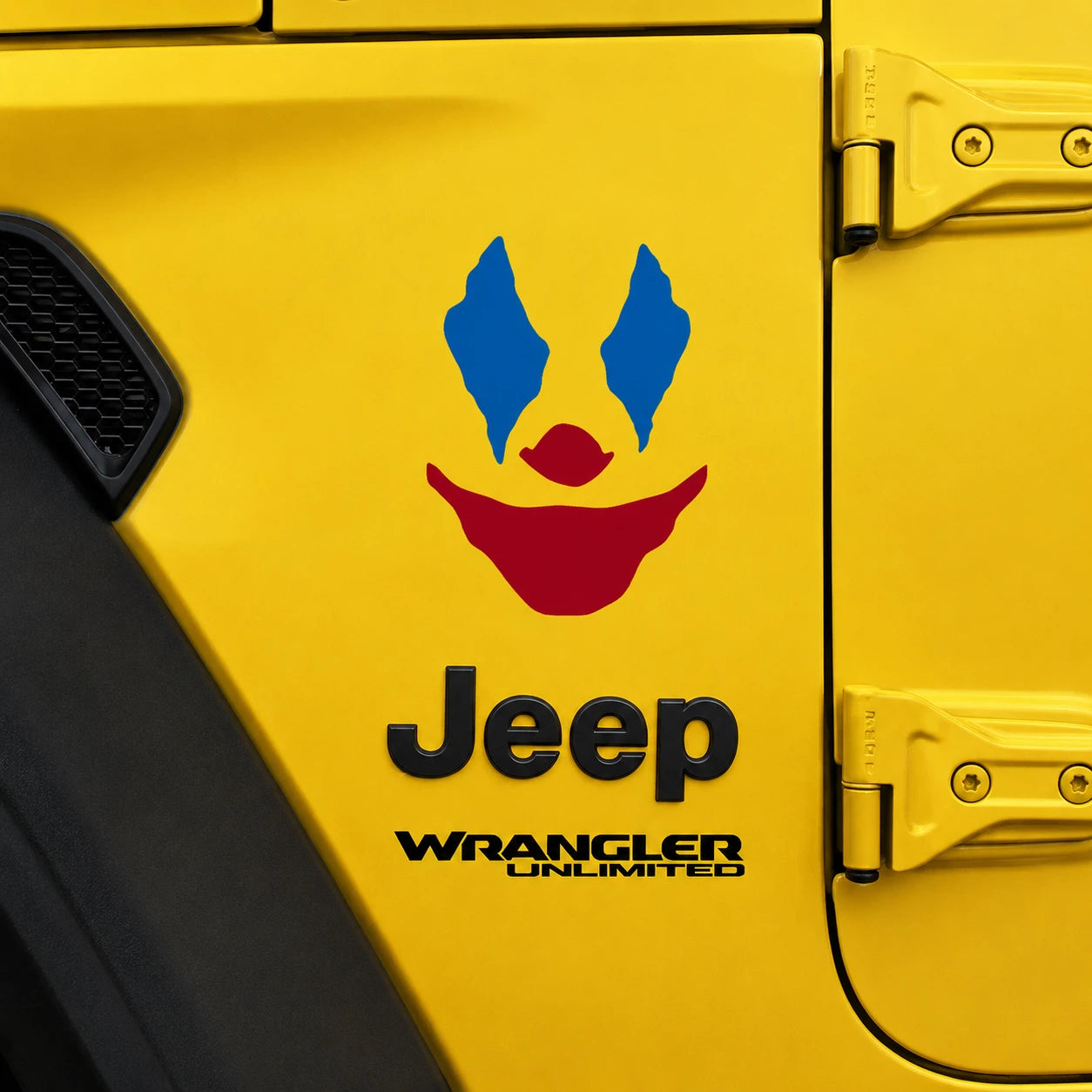 Clown face joker vinyl decal close-up on yellow Jeep Wrangler JL front fender showing blue eyes and red mouth detail