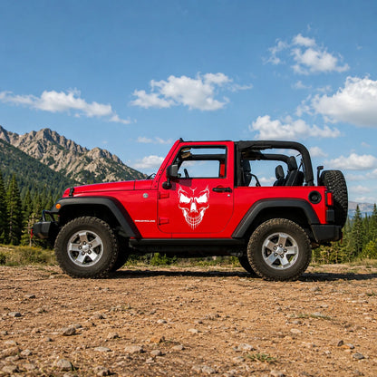Demon skull vinyl decal installed on red Jeep Wrangler 2-door full side view in mountain landscape