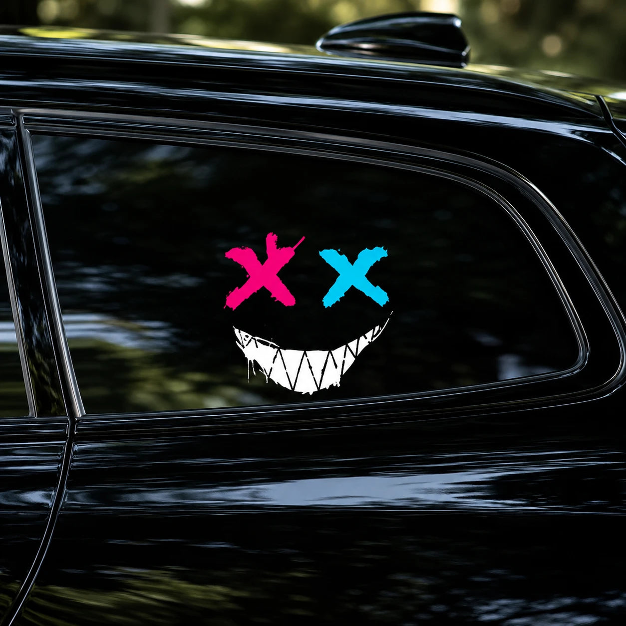 Evil XX smiley face vinyl decal close-up on black car rear side window showing pink X blue X and white jagged grin detail