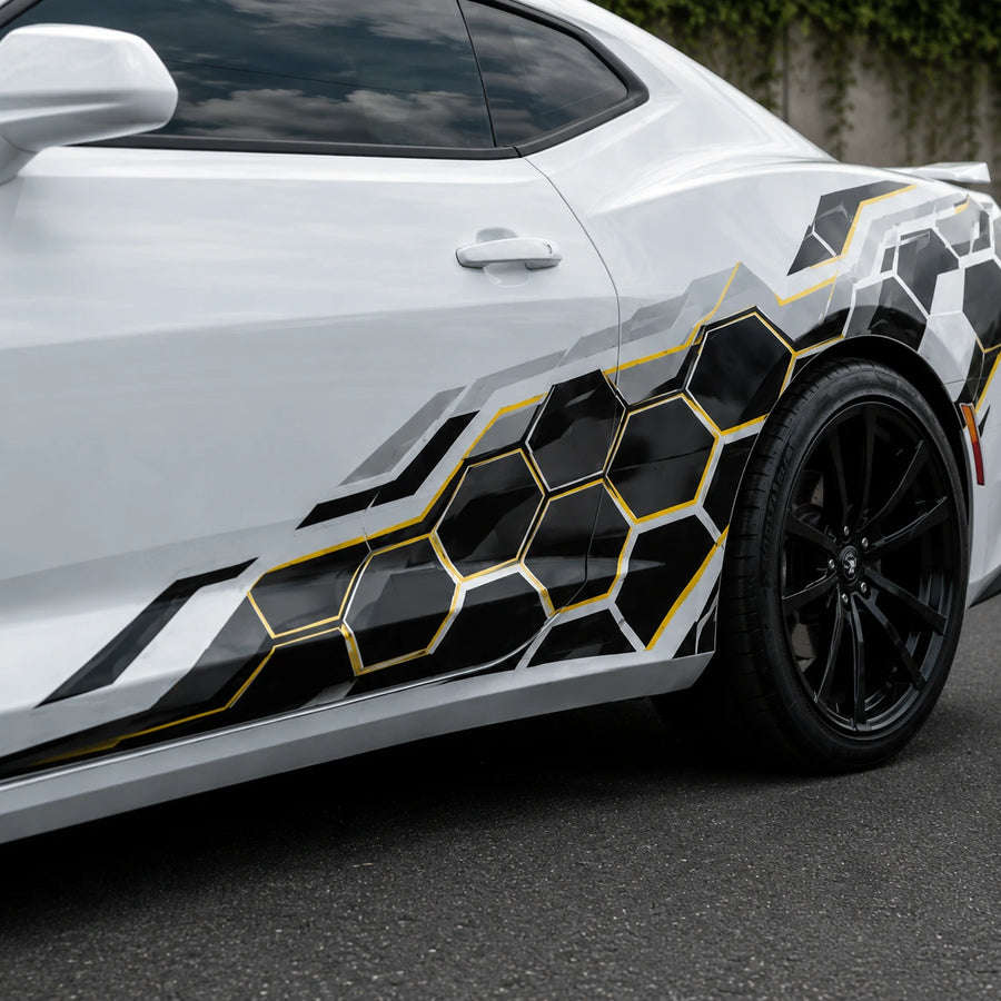 Close-up of black and gold honeycomb hex vinyl decal on white car door panel – detailed geometric pattern view