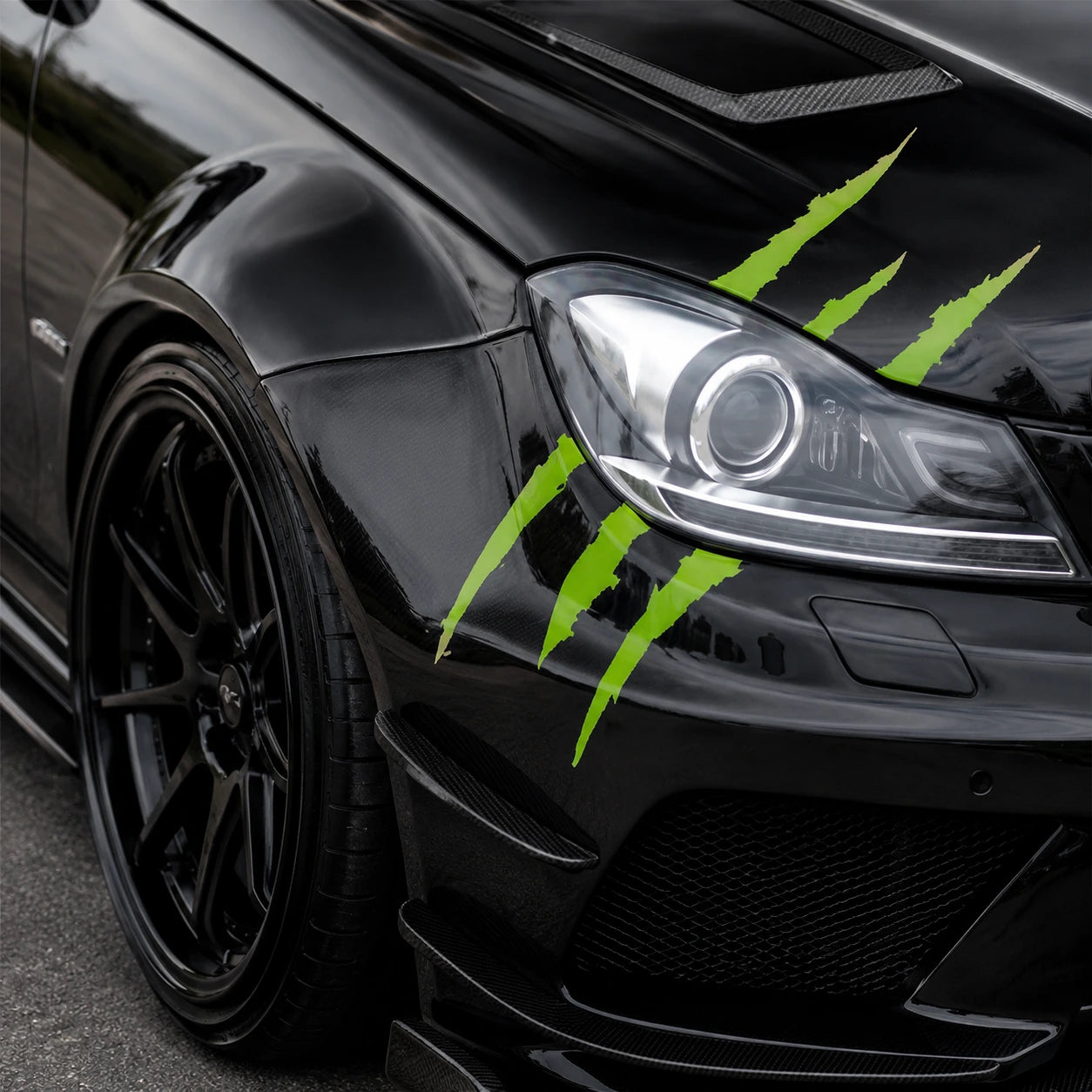 Green monster claw scratch vinyl decal close-up on black Mercedes-Benz C-Class AMG hood and fender showing three razor-sharp claw marks