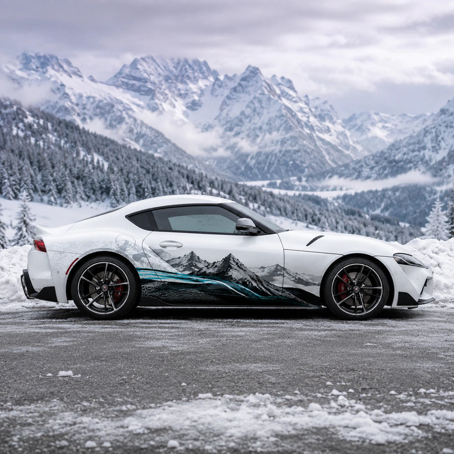 White Toyota Supra GR with mountain landscape side decal – full side profile in snowy alpine mountain valley setting