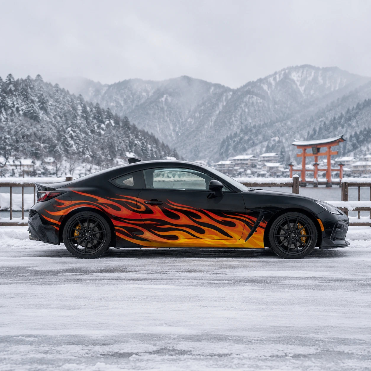 Black Toyota GR86 with orange flame side decal – full side profile by snowy Japanese torii gate and mountain lake