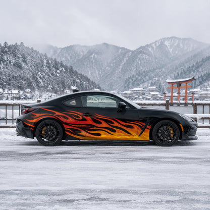 Black Toyota GR86 with orange flame side decal – full side profile by snowy Japanese torii gate and mountain lake