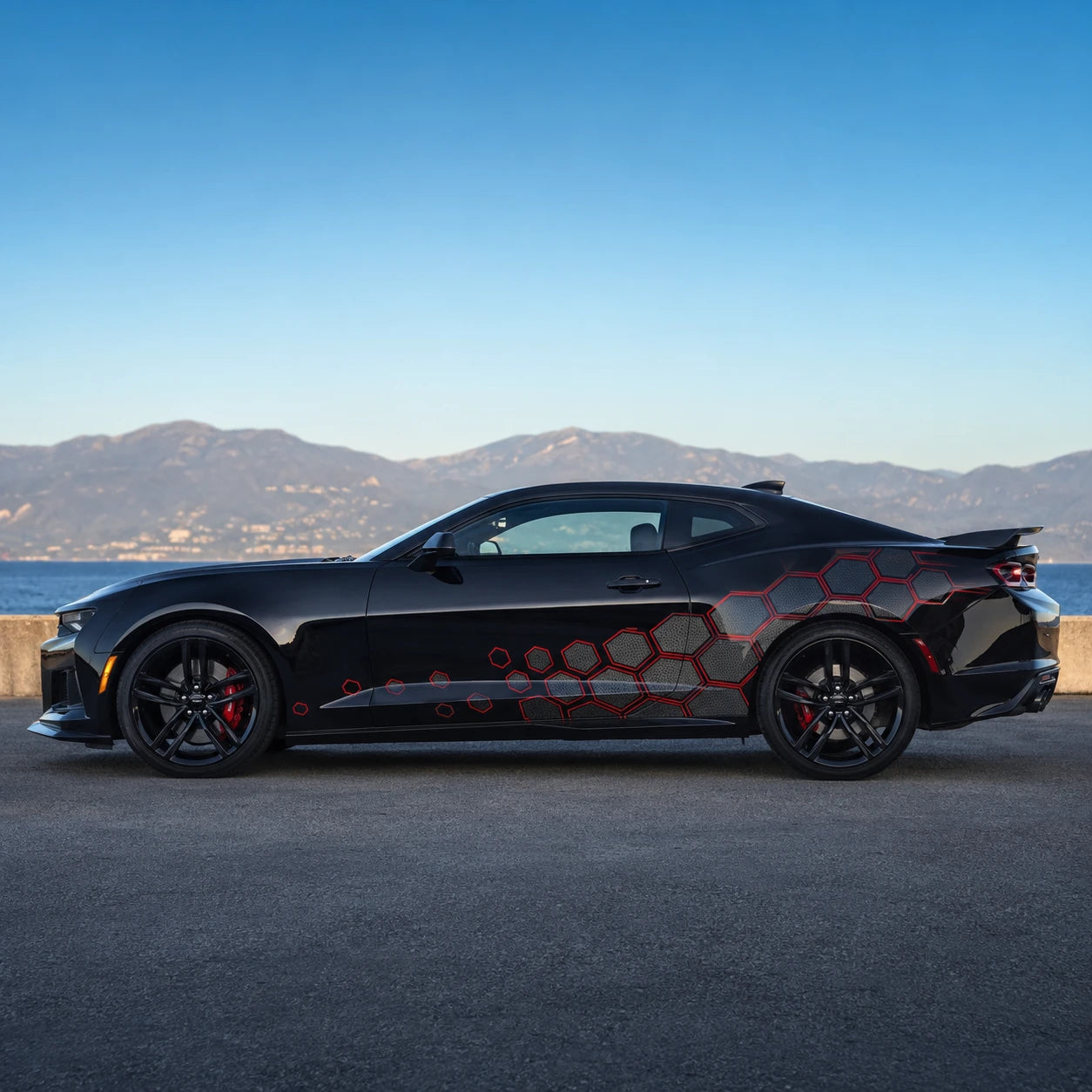 Black Chevrolet Camaro ZL1 with red hex honeycomb side decal – full side profile by Mediterranean coastal road at dusk