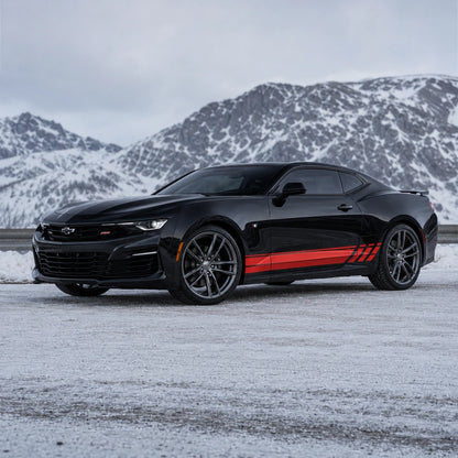 Black Chevrolet Camaro RS with red racing stripe side decal – front 3/4 view in snowy mountain landscape