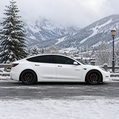 Tesla Model 3 Performance side skirt decal rear three-quarter view in snowy mountain village with church backdrop