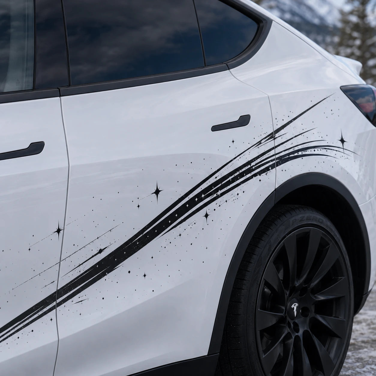 Tesla Model Y shooting star brushstroke decal close-up door panel black ink stroke four-pointed sparkle star ink splatter detail snowy mountain background