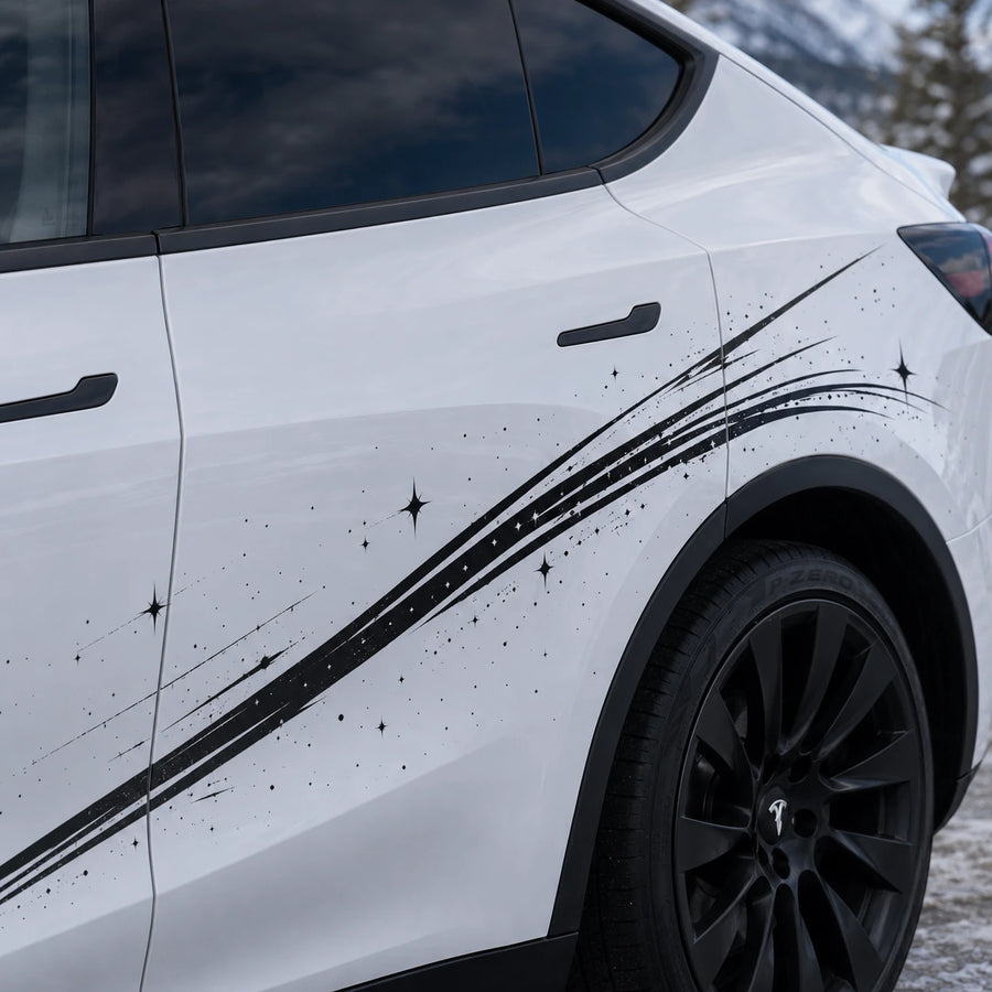 Tesla Model Y shooting star brushstroke decal close-up door panel black ink stroke four-pointed sparkle star ink splatter detail snowy mountain background