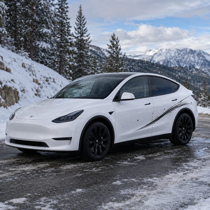 Tesla Model Y shooting star streak side decal front three-quarter view snowy mountain pine forest road winter background black brushstroke sparkle