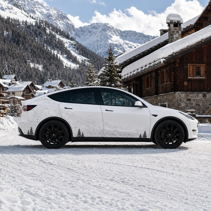 Tesla Model Y topographic contour line car decal full side view snowy alpine mountain chalet background pine tree silhouette