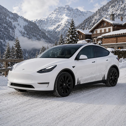 Tesla Model Y topographic mountain pine tree decal front three-quarter view snowy alpine chalet mountain village winter background
