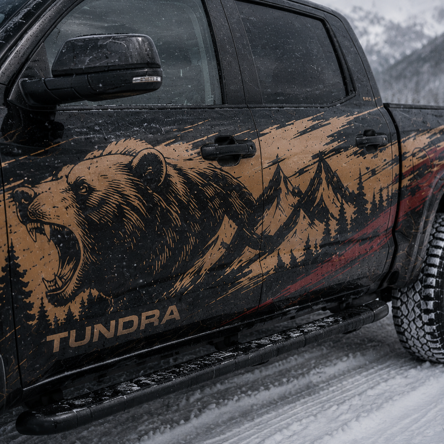 Close-up of Toyota Tundra door panel showing detailed roaring grizzly bear with mountain and pine forest decal in tan and black with TUNDRA lettering in snow