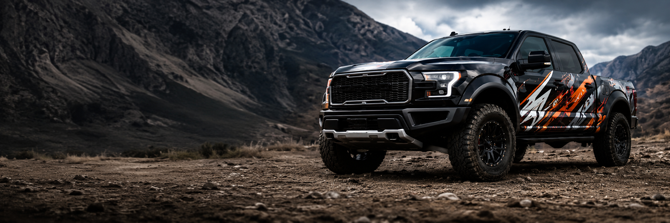 Black Ford Raptor truck with custom orange and gray camo vinyl decals on rocky mountain terrain – WEEM Custom vehicle decals for cars, trucks, Jeeps and commercial vehicles